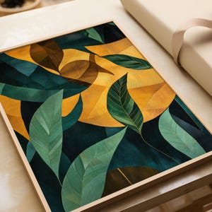 Op de afbeelding: Een ingelijste kunstdruk met een abstract botanisch ontwerp. Het kunstwerk toont gestileerde bladeren in tinten groen, bruin en geel tegen een donkerblauwe achtergrond. De print is ingekaderd in een lichtgekleurde houten lijst, wat een moderne esthetiek creëert.