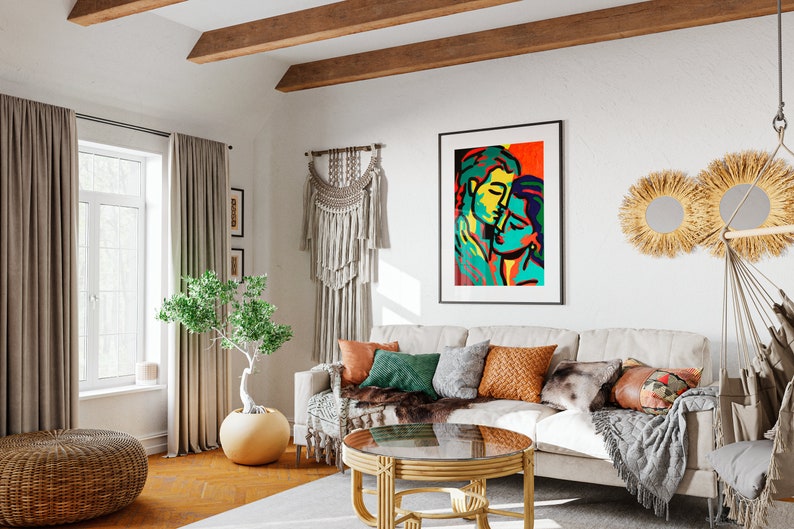 K&ouml;nnte beinhalten: Ein Wohnzimmer mit einem beigen Sofa, einem Couchtisch, einer Topfpflanze und einem gerahmten abstrakten Gem&auml;lde von zwei Personen. Der Raum hat einen Boho-Stil mit einem Makramee-Wandbehang, einem gewebten Teppich und einem Korbstuhl.