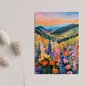 May include: A painting of a mountain landscape with a field of colorful wildflowers in the foreground. The sky is a vibrant orange and blue, and the mountains are a deep green. The flowers are a variety of colors, including pink, purple, yellow, and orange.