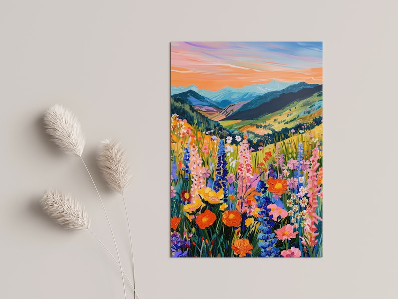 May include: A painting of a mountain landscape with a field of colorful wildflowers in the foreground. The sky is a vibrant orange and blue, and the mountains are a deep green. The flowers are a variety of colors, including pink, purple, yellow, and orange.