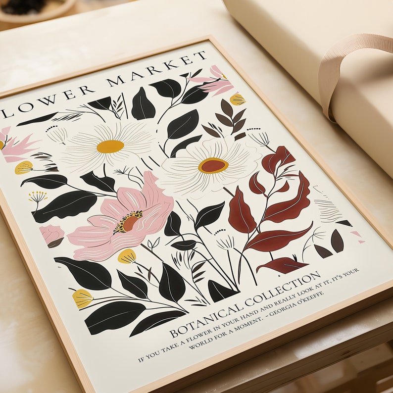 May include: A framed print with a floral design featuring pink, white, and yellow flowers with black and brown leaves. The print has the text "LOWER MARKET" and "BOTANICAL COLLECTION" with a quote by Georgia O'Keeffe.
