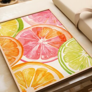 May include: A framed watercolor print featuring vibrant citrus fruit slices. The artwork showcases oranges, grapefruits, and limes in shades of orange, pink, yellow, and green. The wooden frame adds a natural touch to the colorful fruit design.