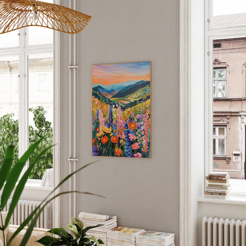 May include: A painting of a mountain landscape with a field of colorful wildflowers in the foreground. The sky is a vibrant orange and pink, and the mountains are a deep blue. The flowers are a mix of pink, purple, yellow, and orange.