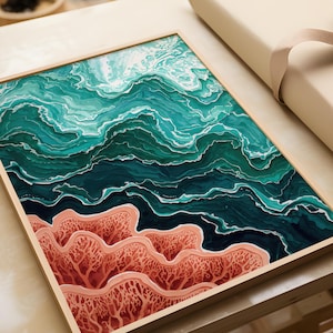 Pode incluir: Impressão de arte abstrata com uma cena oceânica. A obra apresenta ondas turquesas e verde-azulado escuro sobre formações semelhantes a corais em tons de pêssego e vermelho. A impressão é emoldurada em uma moldura de madeira clara.