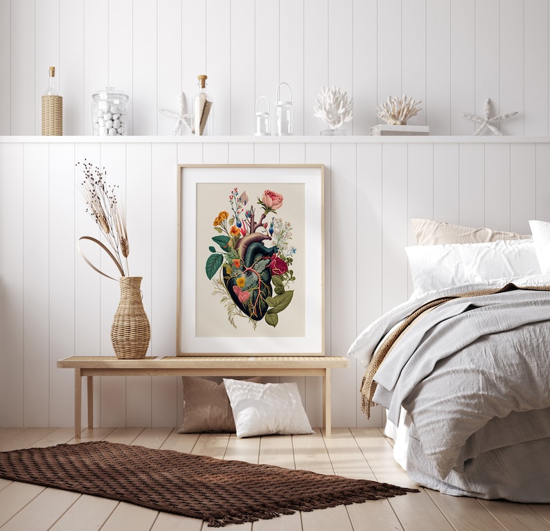 May include: A framed botanical print of a human heart with flowers growing from it. The heart is dark green and the flowers are pink, red, yellow, and white. The print is on a white background and is framed in a simple white frame.