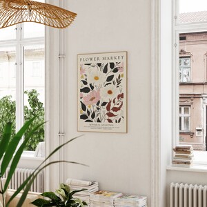 May include: A poster with the title "FLOWER MARKET" featuring a botanical illustration of white and pink flowers with dark green and burgundy leaves. The text "BOTANICAL COLLECTION" is at the bottom of the poster.