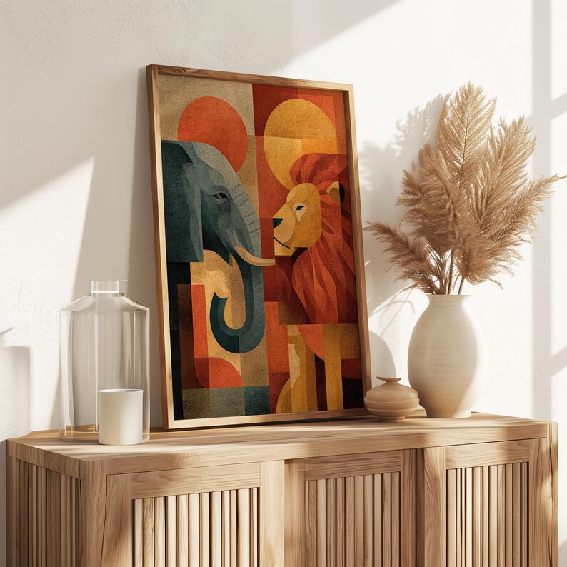 May include: Framed art print featuring a geometric design of an elephant and a lion. The artwork uses a palette of orange, yellow, and teal, with a wooden frame. The print is displayed on a wooden cabinet, with a vase of dried flowers and decorative items.