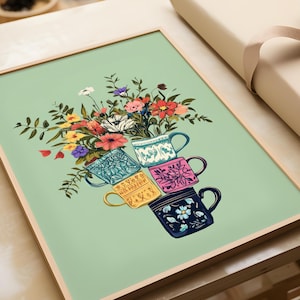 Può includere: Una stampa artistica incorniciata con un bouquet di fiori colorati che fuoriescono da una pila di tazze da tè decorative. Le tazze sono blu, rosa, gialle e blu navy, ognuna con motivi floreali unici. Lo sfondo è verde chiaro.