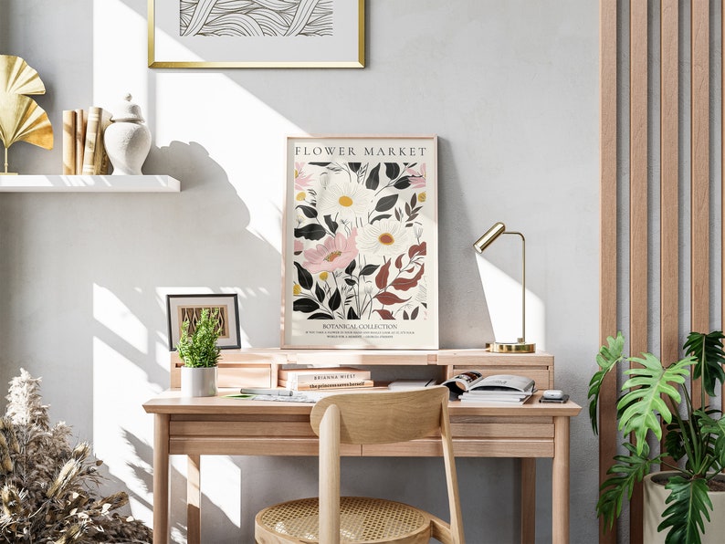May include: A light wood desk with a gold lamp, a potted plant, and a framed print of flowers with the text "FLOWER MARKET BOTANICAL COLLECTION".