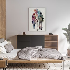 以下が含まれることがあります： 鑑賞者から見て、手を繋いで歩き去るカップルの水彩画。絵は黒の額縁で飾られ、木製のドレッサーの上の白い壁にかけられている。