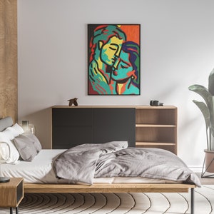 K&ouml;nnte beinhalten: Ein Schlafzimmer-Interieur mit einem Bett, einer Kommode, einer Pflanze und einem gerahmten abstrakten Gem&auml;lde von zwei sich umarmenden Personen. Das Gem&auml;lde ist in einem schwarzen Rahmen und zeigt leuchtende Farben, darunter Rot, Orange, Gelb, Gr&uuml;n und Blau.