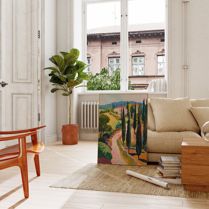 Puede incluir: Una pintura de un camino sinuoso a trav&eacute;s de un paisaje verde con altos cipreses. La pintura est&aacute; enmarcada en un marco dorado y est&aacute; colgada en una pared blanca en una sala de estar.