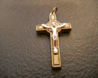 May include: A gold-toned metal crucifix pendant with a silver-toned Jesus figure. The crucifix has a circular design in the center.