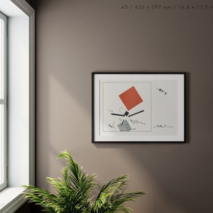 May include: A framed art print featuring a geometric abstract design with a red square, black lines, and gray shapes on a white background. The print is in a black frame and is displayed on a brown wall near a window and a green plant.