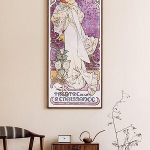 May include: A vintage poster for a play called "La Dame Aux Camelias" starring Sarah Bernhardt. The poster features a woman in a white dress with a flower in her hand, standing in front of a purple background with stars. The text "Theatre de la Renaissance" is at the bottom of the poster.