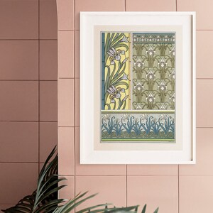 May include: A framed print of a vintage botanical illustration featuring a repeating pattern of stylized iris flowers in shades of green, white, and yellow. The print is in a white frame and is hanging on a pink tiled wall.