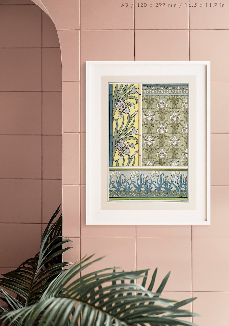 May include: A framed print of a vintage botanical illustration featuring a repeating pattern of stylized iris flowers in shades of green, white, and yellow. The print is in a white frame and is hanging on a pink tiled wall.