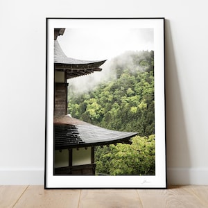 May include: A black and wooden Japanese temple roof with a view of a lush green forest with fog in the background.