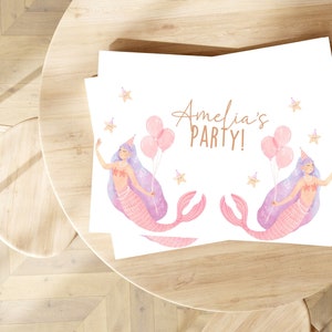 May include: A white card with a pink mermaid illustration and the text "Amelia's Party!" in copper lettering. The mermaid is holding pink balloons and has a pink and purple tail.