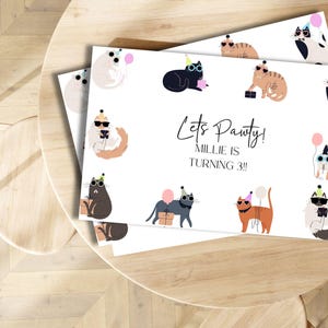 Pu&ograve; includere: Carta bianca con un tema di festa di gatti. La carta ha un gatto bianco e nero con occhiali da sole e un cappello da festa. Il testo sulla carta dice "Let's Pawty! Millie is turning 3!"