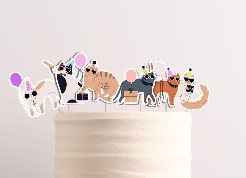 Pu&ograve; includere: Una torta bianca con sei topper a forma di gatto. I gatti indossano cappelli da festa e occhiali da sole. La torta &egrave; decorata con palloncini rosa e viola.