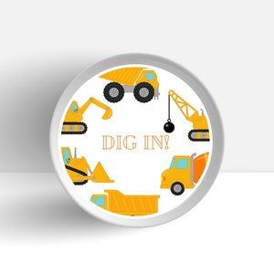 May include: A white round plate with a yellow and orange construction theme. The plate features a variety of construction vehicles including a dumper truck, a crane, a bulldozer, and a cement mixer. The text "DIG IN!" is printed in orange in the centre of the plate.