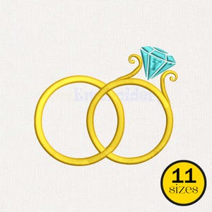 May include: A gold-colored ring design with a large, light blue diamond and a second interlocking ring. The design includes a small, yellow circle with the text "11 sizes". This image is suitable for embroidery or digital design projects.
