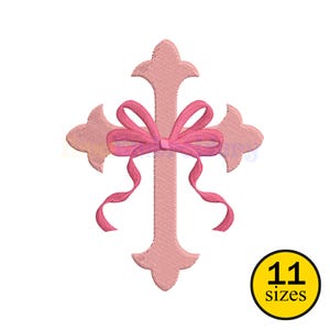 May include: A light pink cross design with a pink bow in the center and flowing ribbons. The cross has decorative edges. A yellow circle with the text "11 sizes" is in the lower right corner.