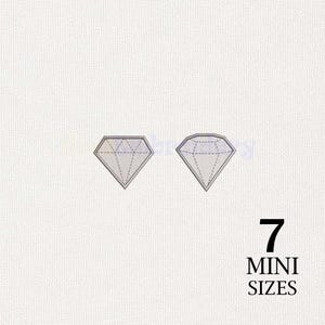 Puede incluir: Dos diseños de bordado a máquina en forma de diamante con contornos grises y relleno gris claro. El texto 7 MINI SIZES está impreso en negro en la esquina inferior derecha sobre un fondo de tela blanca texturizada.