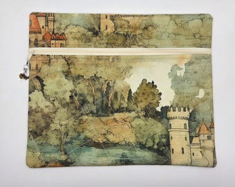 May include: A rectangular fabric zipper pouch featuring a printed landscape of a medieval castle, lush green trees, and a river. The pouch has a cream-colored zipper closure with a small metal charm attached to the pull tab and a diamond-stitched quilted pattern.