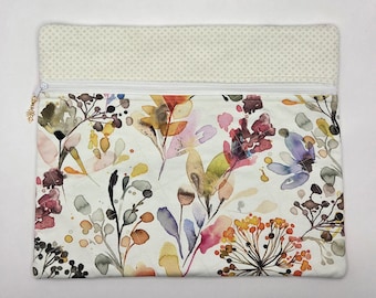 May include: A rectangular zippered pouch featuring a white background with a colorful watercolor floral print. The top section has a light beige fabric with a small cross pattern. A white zipper runs across the top with a small gold flower charm.