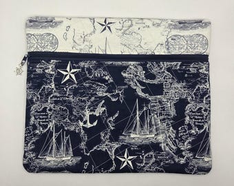 May include: A rectangular zippered pouch featuring a dark navy blue fabric with a white nautical map print, including sailing ships, anchors, and stars. The top flap is made of a cream-colored fabric with a matching map design and a ship's wheel charm.