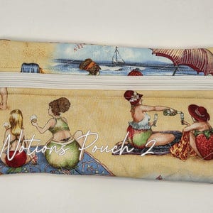 May include: A rectangular fabric pouch with a white zipper and a silver starfish charm. The pouch features a beach scene print with people, umbrellas, and strawberries, and the text Notions Pouch 2 printed in white script across the center.