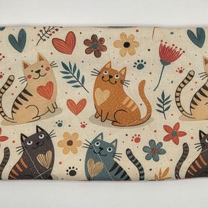 May include: A rectangular quilted fabric pouch featuring a repeating pattern of cats in shades of tan, gray, and black, interspersed with red hearts, colorful flowers, and green leaves on a cream background, finished with a silver daisy zipper pull.