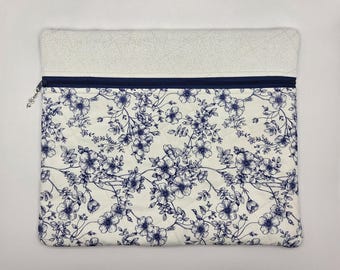 May include: A rectangular quilted fabric pouch featuring a cream background with a dark blue floral pattern. The top section is a solid cream fabric with a subtle texture. A dark blue zipper runs across the width, finished with a small silver charm.