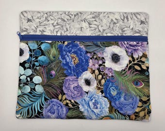 May include: A rectangular zippered pouch featuring a top section with a gray and white leaf pattern and a bottom section with a black background printed with blue and purple peonies, peacock feathers, and gold accents, finished with blue stitching.