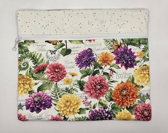 May include: A rectangular zippered pouch featuring a botanical print of purple, yellow, orange, and pink dahlia flowers with green foliage and butterflies on a white background, topped with a cream-colored fabric panel with small red dots.