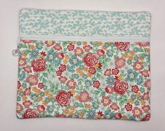 May include: A rectangular zippered pouch featuring a two-part design. The top section has a light blue and white floral pattern, while the larger bottom section displays a dense print of red roses, yellow blossoms, and blue flowers on white.