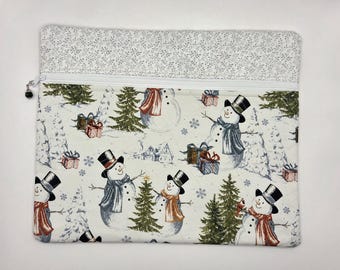 May include: A rectangular fabric zipper pouch featuring a winter scene with snowmen wearing top hats and scarves, green pine trees, and gift boxes on a cream background. The top section has a light gray floral pattern and a white zipper closure.