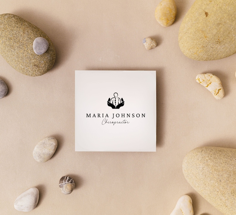 May include: A white business card with a black logo of a person with hands raised above their head. The text "MARIA JOHNSON Chiropractor" is printed below the logo.