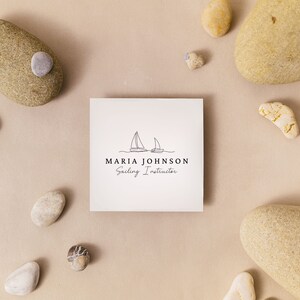 Puede incluir: Una tarjeta blanca con un dibujo simple de dos veleros en una ola. El texto "MARIA JOHNSON Sailing Instructor" est&aacute; debajo de la imagen.