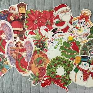May include: A collection of Christmas-themed die-cut paper decorations. The images include Santa Claus, angels, snowmen, poinsettias, wreaths, and a clock with the text "It's Time For Christmas". The color palette is red, green, white, and gold.