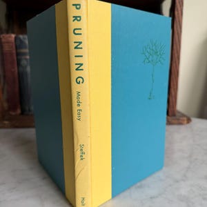 May include: A hardcover book titled Pruning Made Easy by Steffek, published by Holt. The book features a bright yellow spine with dark blue text and a teal blue cover with a simple green line drawing of a leafless tree on the front panel.