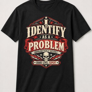 May include: A black short-sleeved t-shirt featuring a graphic design with the text I IDENTIFY AS A PROBLEM, UNAPOLOGETICALLY DIFFICULT, and CHAOS LEVEL: EXPERT. The design includes a central skull illustration, red banners, and white lettering.