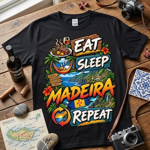 Puede incluir: Una camiseta negra de manga corta con un estampado gráfico colorido y el texto EAT SLEEP MADEIRA REPEAT. El diseño incluye ilustraciones de una copa de vino, una hamaca, un paisaje costero, la bandera de Madeira y un mapa de la isla.
