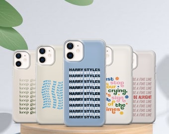 May include: Five different phone cases with various designs. The cases are all clear and show the phone's camera lens. The designs include a repeating pattern of "Harry Styles" in blue text, a pattern of "Be a Fine Line" in rainbow text, a pattern of "Well Be Alright" in blue text, a pattern of "Keep Going" in blue text, and a pattern of "This is our stop, crying, a sign of the times" in rainbow text.