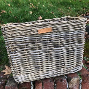 May include: A large, rectangular wicker basket with a light grey wash finish. The basket has a leather tag with the text "RT Living" on it.