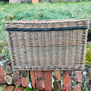 May include: A large, rectangular wicker basket with a dark brown woven pattern and a black rope trim around the top.
