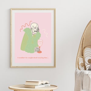 Pu&ograve; includere: Un'illustrazione rosa e verde di uno scheletro che indossa un cappotto di pelliccia e tiene un bicchiere di vino. Il testo sotto l'immagine dice "Non mi troverebbero morto a indossare questo..."