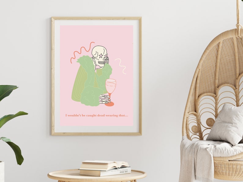 Pu&ograve; includere: Un'illustrazione rosa e verde di uno scheletro che indossa un cappotto di pelliccia e tiene un bicchiere di vino. Il testo sotto l'immagine dice "Non mi troverebbero morto a indossare questo..."